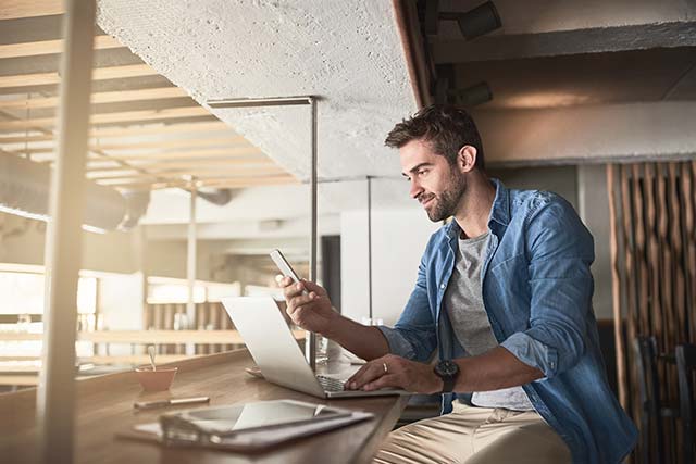 A young male entrepreneur checking his cell phone while working